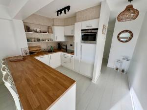 una cucina con mobili bianchi e un tavolo di legno di BEACH apartment met directe toegang tot het STRAND ! a Knokke-Heist Altre 31 foto