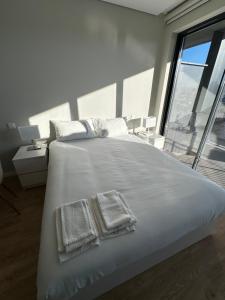 a bedroom with a large white bed with towels on it at New Douro Tower 305 with shared pool and parking in Vila Nova de Gaia