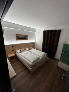a small bedroom with a bed and wooden floors at Tilde in Tesero