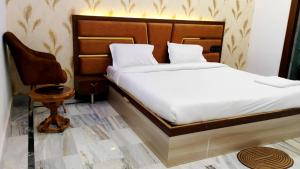 ein Schlafzimmer mit einem Bett und einem Stuhl in der Unterkunft Hotel Premimum Kashi Satya Luxury-Parking Facility #Near KASHI VISHWANATH TEMPLE# in Varanasi
