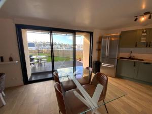 sala de estar con mesa de cristal y cocina en Appartement avec son jardin face au port d'Audierne, en Plouhinec 35 fotos más