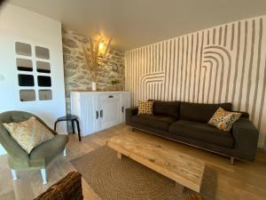 una sala de estar con un sofá y una silla en Appartement avec son jardin face au port d'Audierne, en Plouhinec
