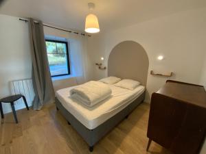 Un dormitorio con una cama y una ventana y una mesa. en Appartement avec son jardin face au port d'Audierne, en Plouhinec