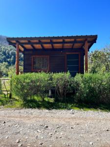 a small cabin with a roof on a dirt road at Camping Aiton Amunak in El Bolsón