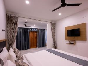 Un dormitorio con una cama y un televisor de pantalla plana. en Puthooram Seaview Cliff Resort, en Varkala