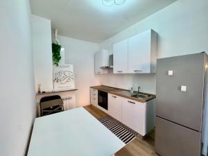 a kitchen with white cabinets and a stainless steel refrigerator at Le due dimore di Corso Torino in Novara