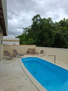 einen Pool auf einer Terrasse mit Stühlen neben einem Gebäude in der Unterkunft Casa de Campo com piscina Ninho Verde 2 in Pardinho