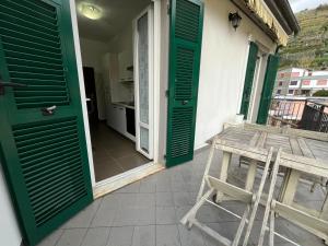 ヴェルナッツァにあるOld Town Roomsの緑色のドアと木製のテーブルとスツールのあるポーチ