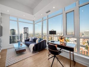 a living room with a couch and a desk and windows at Sovitel Suites - Toronto's Entertainment District in Toronto +34 photos