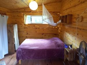 a bedroom with a bed in a wooden cabin at Chalets rustiques en pleine nature, L'ARCHIPEL in Punta Del Diablo