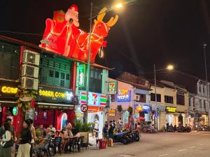 een stadsstraat 's nachts met mensen die aan tafel zitten bij Just House - Rooms & Curios in George Town
