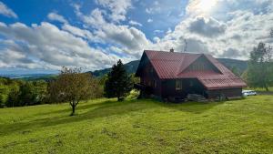 a red barn on a hill with a green field at Penzion Soukupovi in Strážné