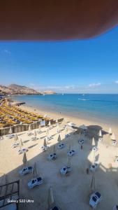 a beach with white umbrellas and chairs and the ocean at Pyramids Porto Sokhna Hotel Apartments in Ain Sokhna +23 photos