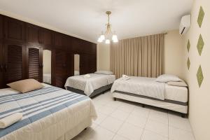 Un dormitorio con dos camas y una lámpara de araña. en Go Bed & Breakfast, en San Pedro Sula