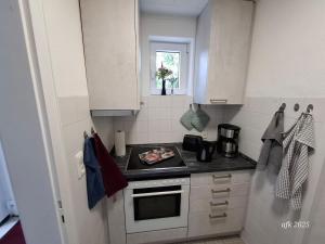a small kitchen with white cabinets and a stove at Casa-Flores, um"Schwarzes Gold" zu erkunden in Bad Fallingbostel