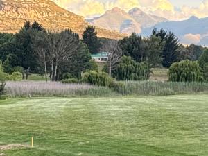un champ d'herbe avec des montagnes en arrière-plan dans l'établissement 127 Clarens Golf Villa, à Clarens
