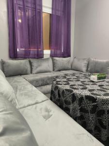 un sofá en una sala de estar con cortinas moradas en Younes residence, en Asilah