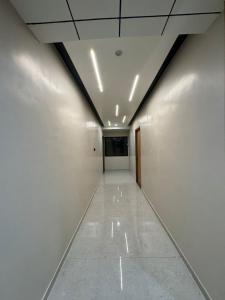 a long hallway with white walls and a ceiling at OM Hotel in Sirohi