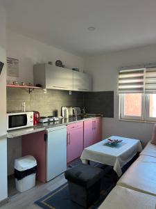 a kitchen with pink and purple cabinets and a couch at Apartman Orhan in Mostar
