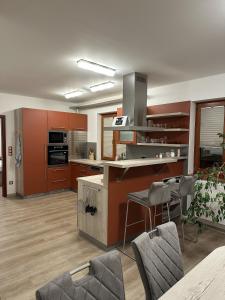 a kitchen with orange cabinets and a counter with chairs at Apartmán U3 in Týniště nad Orlicí