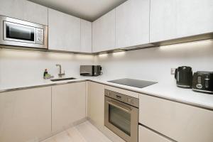 a kitchen with white cabinets and a sink and a microwave at Modern 1 Bed Apt Bracknell- with parking in Bracknell
