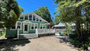 a green house with a porch and a house at Sandy Shores in Union Pier