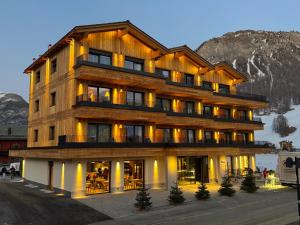 a large wooden building with a mountain in the background at Hotel Damelis - Adults Only in Livigno