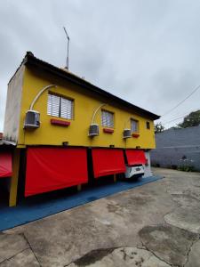 una casa amarilla y roja con garaje rojo en Hotel-Motel Novo Oasis, en São Paulo