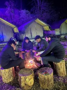 un grupo de personas sentadas alrededor de un fuego en una tienda en Royal Mount, en Kasol