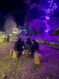 un grupo de personas sentadas en una mesa por la noche en Royal Mount, en Kasol