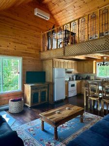 eine Küche und ein Wohnzimmer mit einem Tisch in einer Hütte in der Unterkunft Le repère de la Rivière in Saint-Alexis-des-Monts
