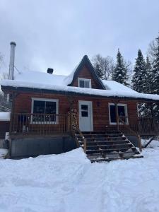 eine Blockhütte mit Schnee auf dem Dach in der Unterkunft Le repère de la Rivière in Saint-Alexis-des-Monts