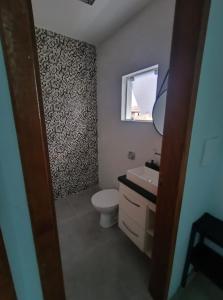 een badkamer met toilet, wastafel en raam bij Sobrado 3 Condomínio Sobre as Ondas, 4min a pe da Praia in Guaratuba