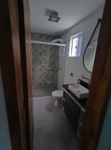 een badkamer met een toilet, een wastafel en een spiegel bij Sobrado 3 Condomínio Sobre as Ondas, 4min a pe da Praia in Guaratuba