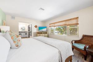 een slaapkamer met een bed, een stoel en een raam bij Blue Ocean Suites by Beachside Management in Siesta Key