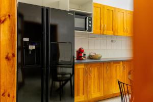 a black refrigerator in a kitchen with wooden cabinets at T3 Duplex - Tsimkoura in Chirongui