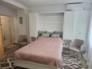 een slaapkamer met een groot bed en twee stoelen bij East apartment in Tecuci