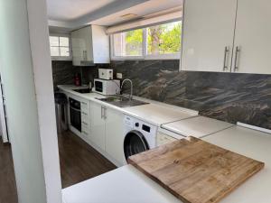 una cucina con mobili bianchi e un lavandino di Apto con piscina y barbacoa a La Alcayna