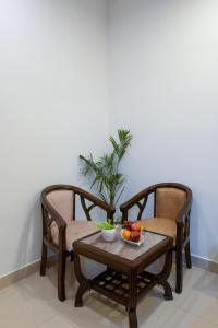 ニューデリーにあるHotel Lemon Pride Aerocity FREE AIRPORT DROPの椅子2脚、テーブル1台(フルーツ1杯付)