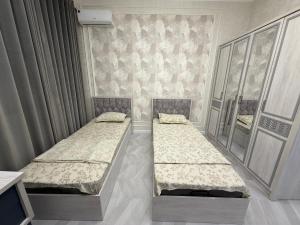 2 camas individuales en una habitación con cortinas en Tashkent City Apartments E2, en Tashkent