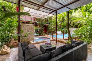 Private Villa with Pool & Heated Jacuzzi, AC, Jungle Garden Near Amenities & Beach في Talamanca: فناء مع أريكة وحمام سباحة