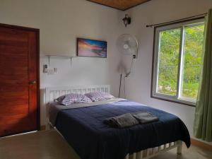 ein Schlafzimmer mit einem Bett mit blauen Laken und einem Fenster in der Unterkunft Little Shark bungalow in Ban Bang Bao