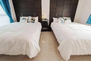 duas camas uma ao lado da outra em um quarto em Sunstone Residence 2F - Free Rental Car included! em Ginowan