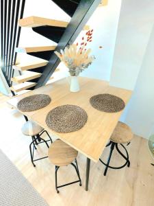 MarcyにあるLogement tout confort au calme dans un ancien Fenilの木製のテーブルと椅子、そして花の入った花瓶