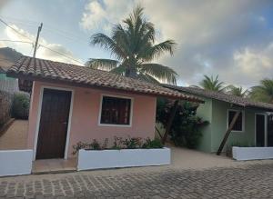 a small house with a palm tree in front of it at Villa Búzios in Nísia Floresta