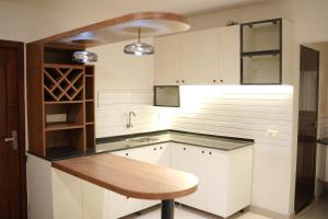 a kitchen with white cabinets and a wooden table at Invito Beach Resort in Kannur