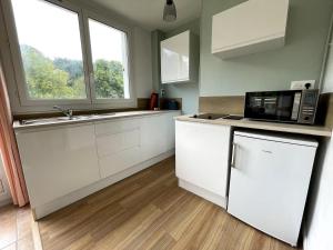 eine Küche mit weißen Schränken und einer Mikrowelle in der Unterkunft Charmant logement avec parking privé - proche village et plage - Veules-les-Roses in Veules-les-Roses + 7 Fotos