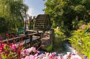 eine Brücke über einen Bach in einem Garten mit Blumen in der Unterkunft Charmant logement avec parking privé - proche village et plage - Veules-les-Roses in Veules-les-Roses