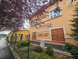 ein Gebäude mit einem Zaun davor in der Unterkunft Harmonia Budget apartman in Dunajská Streda