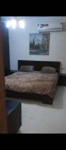 Una cama en un dormitorio con un cuadro en la pared. en شقه مفروشه بالكامل في عمان شارع مكه ضاحيه الأمير راشد, en Amán